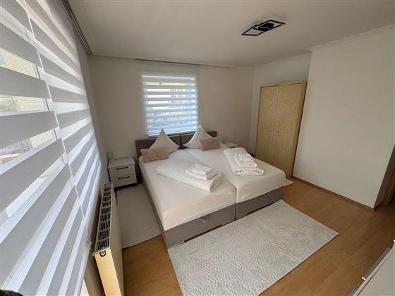 A modern bedroom with a double bed and white bed linens.  
Large windows provide plenty of daylight and a bright, friendly atmosphere.