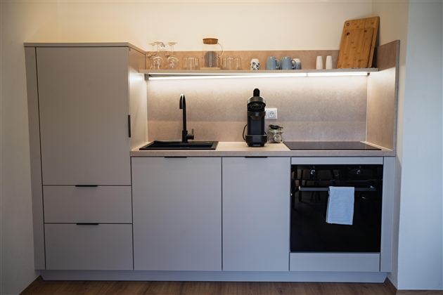 Een moderne keuken met minimalistische meubels en een elegante werkblad. Ze is uitgerust met een kraan, een koffiezetapparaat en een fornuis.