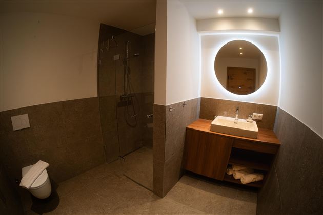 Een moderne badkamer met douche en wastafel. De muren zijn in neutrale kleuren gehouden en er is een gezellige sfeer.