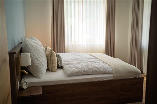 Een gezellige slaapkamer met een groot bed en lichte gordijnen. De inrichting is modern en uitnodigend.