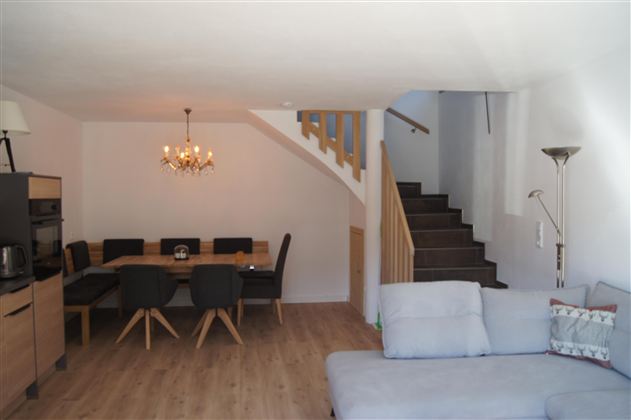 Ein modernes Wohnzimmer mit einem bequemen Couch und einem Essbereich. Eine Treppe führt in den oberen Bereich des Raumes.