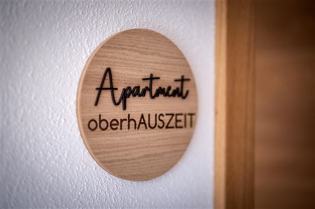 Een houten bord met de tekst "Apartment oberhAUZSEIT".