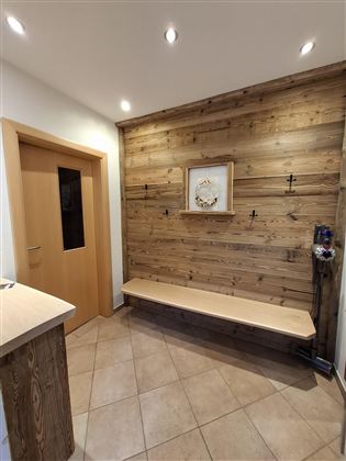 Ein einladender Flur mit einer Holzvertäfelung und einem Sitzbereich. Die Wände sind hell und die Beleuchtung ist warm und freundlich.