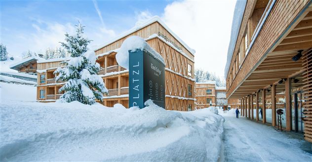 A picturesque hotel in the snow with modern wooden facades.  
The wintry landscape and deeply snow-covered surroundings create a cozy atmosphere.
