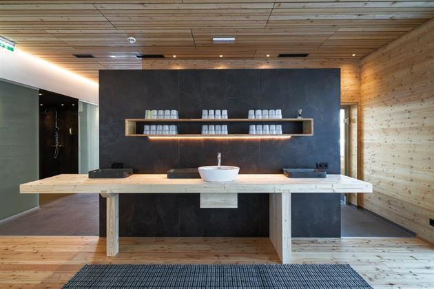 A modern sink in a stylish room with wooden walls. The large wooden table provides space for various utensils and creates a relaxed atmosphere.