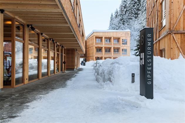 A modern wooden building in a snowy landscape. The snow lies thick on the ground and a clear, peaceful atmosphere can be seen.