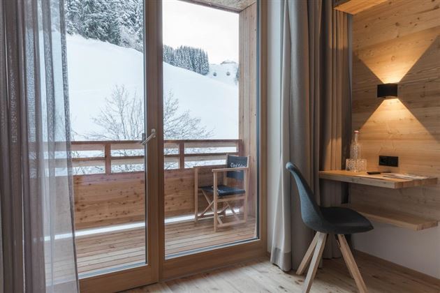 A modern room with a view of a snowy balcony. The room is bright and minimally designed.