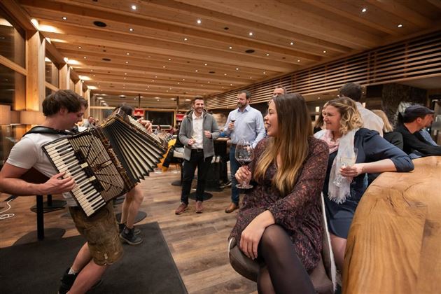 A sociable event in a restaurant with an accordion player.  
Guests enjoy drinks and chat in a warm, inviting atmosphere.