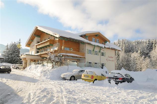 Een sneeuwzeker gebouw temidden van een winterlandschap. Auto's zijn geparkeerd op een besneeuwde parkeerplaats, omringd door met sneeuw bedekte bomen.
