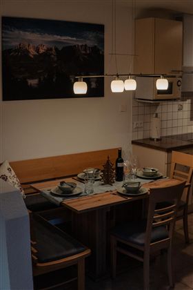 A modern dining room with a wooden table and elegant chairs. Stylish lamps hang above the table in a cozy space.
