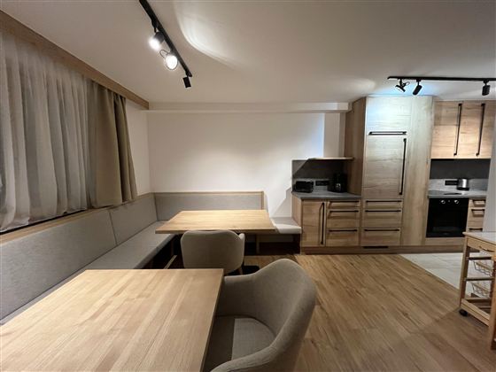 Eine moderne Küche mit Essbereich aus Holz. Helle Möbel und eine einladende Atmosphäre schaffen Gemütlichkeit.