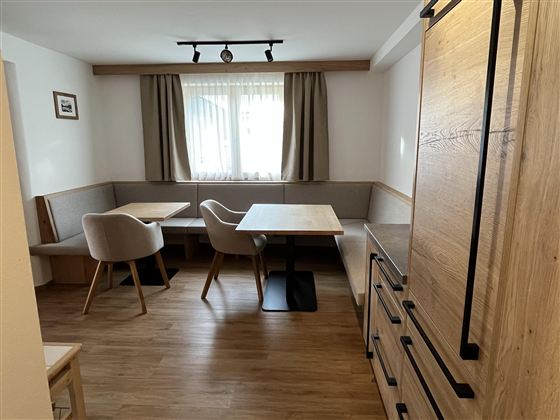 Ein gemütlicher Essbereich mit Holzdesign und modernen Stühlen. Große Fenster sorgen für viel Tageslicht.