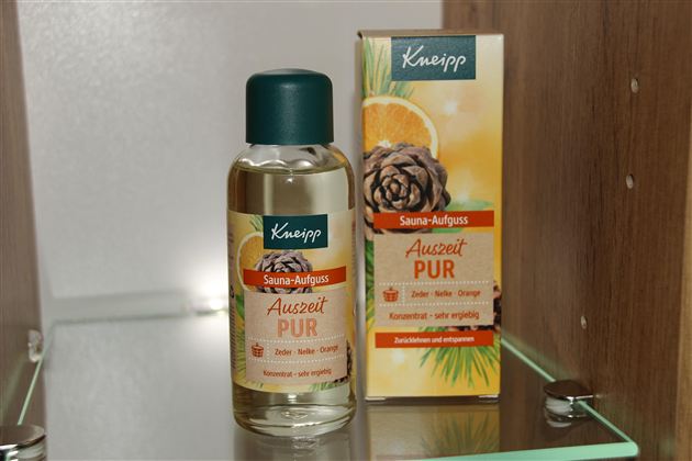 Ein Fläschchen Sauna-Auszug von Kneipp steht neben einer Verpackung. Das Produkt trägt die Bezeichnung "Auszeit PUR" und enthält ätherische Öle.