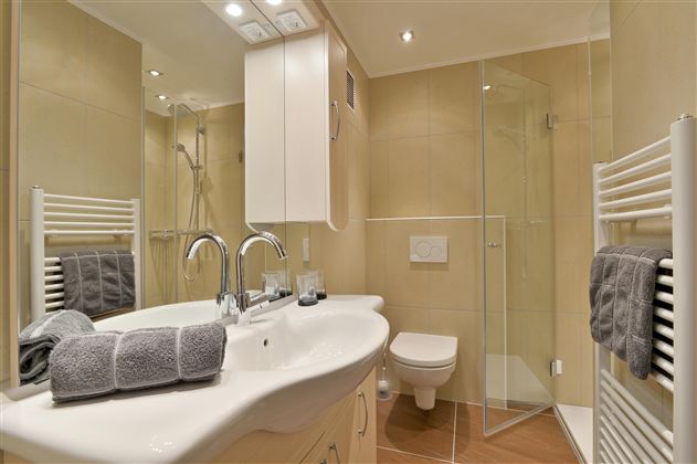 A modern bathroom with a glass shower and a sink. The walls are in neutral colors and decorative towels are neatly arranged.