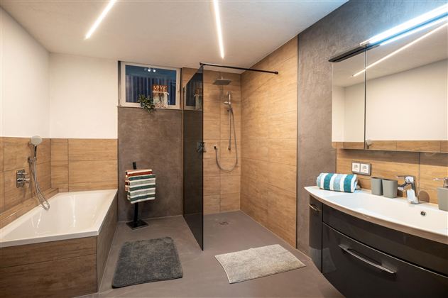 A modern bathroom with a shower and a bathtub. The walls are in neutral tones, complemented by stylish accessories.