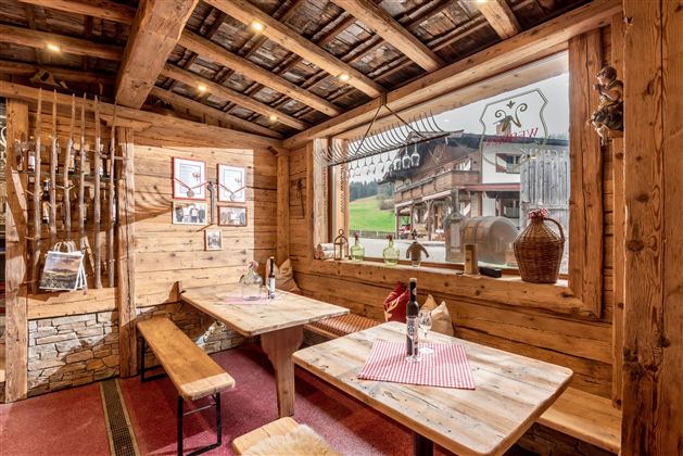 Ein gemütliches Restaurant mit Holzverkleidung und einer einladenden Atmosphäre. Durch das große Fenster sieht man die grüne Landschaft draußen.