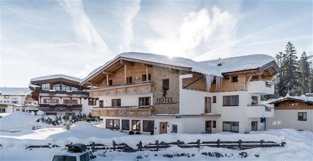 Ein charmantes Hotel in einer verschneiten Landschaft. Umgeben von schneebedeckten Bäumen und klarem Himmel.