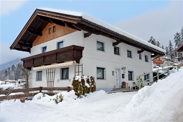 A charming house in the snow with a wooden balcony. The surroundings are wintry and picturesque.