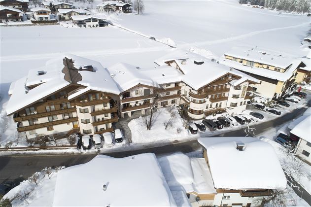 Eine Winterlandschaft mit schneebedeckten Gebäuden und angrenzenden Straßen. Die Szene wirkt friedlich und einladend unter dem weißen Schnee.