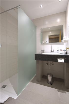 Ein modernes Badezimmer mit einer Glasdusche und einem eleganten Waschtisch. Der Raum ist hell und freundlich gestaltet.