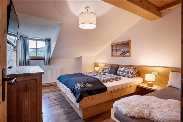 Een gezellige slaapkamer met houten wanden en twee bedden. De kamer heeft grote ramen en een warme sfeer.