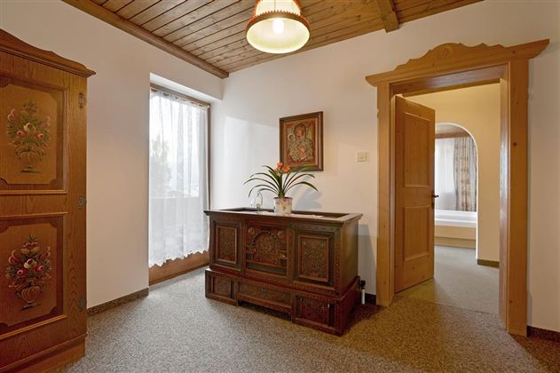 A cozy room with wooden doors and a decorative cabinet. The window provides bright lighting and an inviting atmosphere.