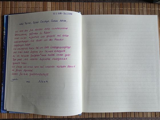 Een geopende notitieboekpagina met handgeschreven tekst in rode en blauwe inkt. De tegenoverliggende pagina is leeg en onbeschreven.