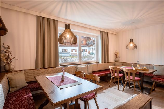 Ein gemütliches Restaurant mit hellen Wänden und Holzdetails. Es gibt Sitzgelegenheiten aus Holz und stilvolle Lampen, die eine warme Atmosphäre schaffen.