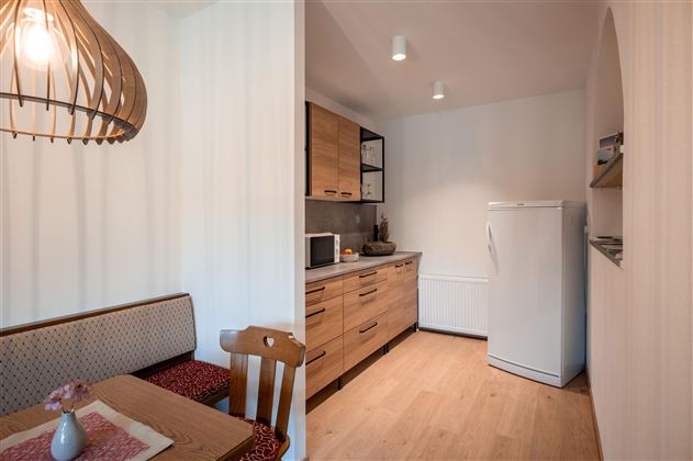 Eine moderne Küche mit Holzschränken und einem Kühlschrank. Ein Esstisch mit Stühlen bietet Platz zum Essen und Entspannen.