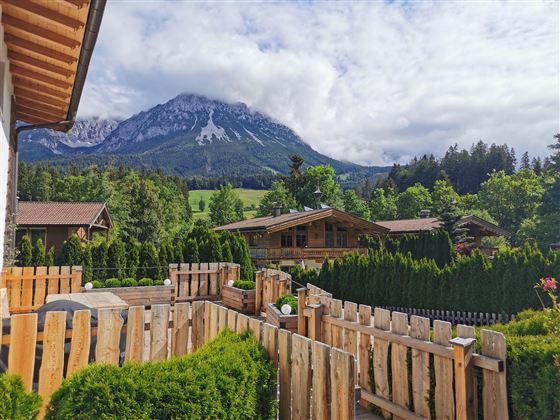 Eine malerische Landschaft mit gut gepflegten Gärten und einem Blick auf majestätische Berge. Die Natur ist grün und einladend, ideal für Erholung und Entspannung.