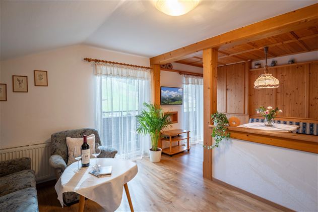 A cozy living space with a sofa and a table. The wooden elements and plants create an inviting atmosphere.