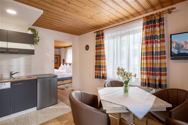 A cozy holiday apartment with a small kitchenette and a dining area.  
Large windows provide bright light and a pleasant atmosphere.