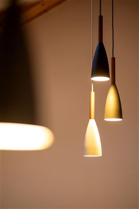 Hängende Lampen in modernen Formen leuchten sanft. Der Hintergrund ist neutral und betont die Beleuchtung.