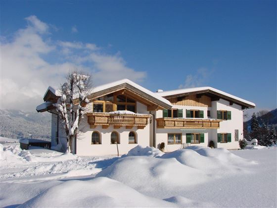 Ein modernes Haus im Schnee, umgeben von einer verschneiten Landschaft. Der klare blaue Himmel verleiht der Winteridylle einen schönen Kontrast.