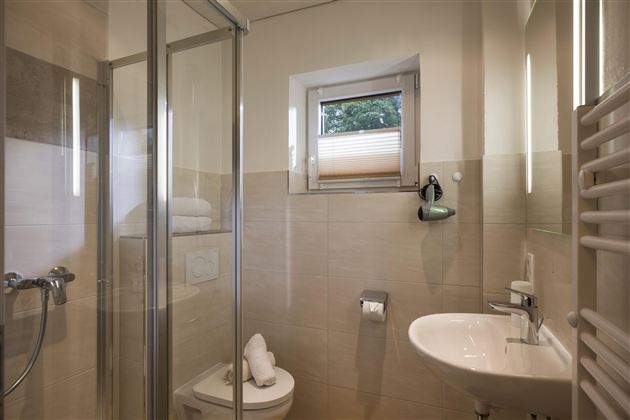 A modern bathroom with a shower and a sink. Bright walls and a window create a friendly atmosphere.