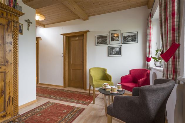 An inviting hallway with colorful armchairs and a small table. Pictures hang on the wall, and a rug adds coziness to the space.