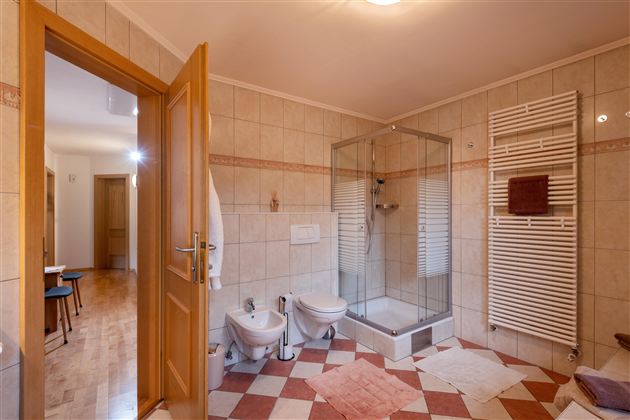 Een modern badkamer met een glasdouche en twee sanitaire voorzieningen. De ruimte is licht en goed verlicht met een houten vloer.