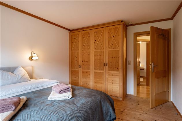 Een gezellige slaapkamer met een groot bed en een houten kast. De kamer heeft een warme, uitnodigende sfeer.