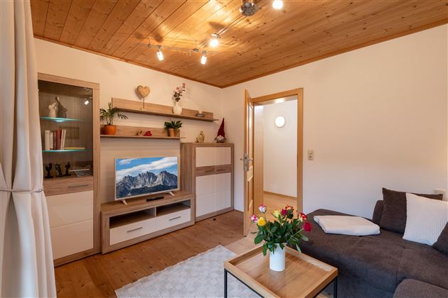 Een gezellige woonkamer met een modern tv-systeem en een comfortabele bank. De ruimte heeft houten wandbekleding en biedt een vriendelijke sfeer.