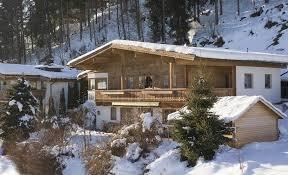 Ein gemütliches Holzhaus im Schnee, umgeben von Bäumen. Die Szene vermittelt eine ruhige, winterliche Atmosphäre.