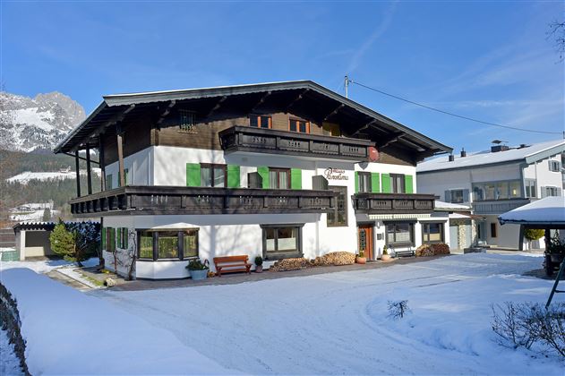 Ein charmantes Gebäude im alpinen Stil, umgeben von Schnee. Die grüne Fensterläden verleihen dem Haus einen besonderen Akzent.