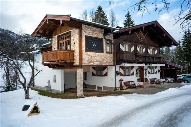 A beautiful chalet in winter, surrounded by snow. The architecture combines traditional and modern elements.