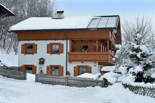 A charming house in alpine style, surrounded by snowy landscape. The wooden shutters and balcony give the building a cozy character.
