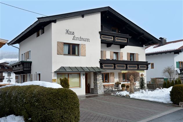 Ein typisches landwirtschaftliches Haus mit dunklem Holz und einem weißen Anstrich. Der Schnee liegt auf dem Boden, und es ist eine ruhige, winterliche Atmosphäre.
