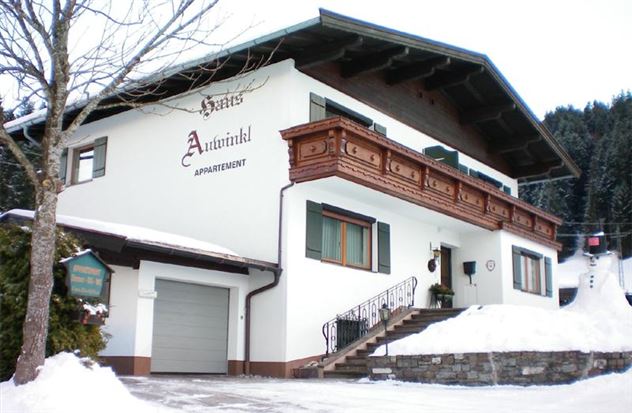 Ein schönes Chalet mit traditioneller Architektur im Schnee. Umgeben von Bäumen und einer Winterlandschaft.