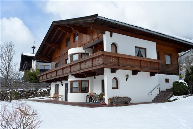 Ein wunderschönes Haus im alpinen Stil, umgeben von Schnee. Der Balkon aus Holz und die Fenster verleihen dem Gebäude einen charmanten Charakter.
