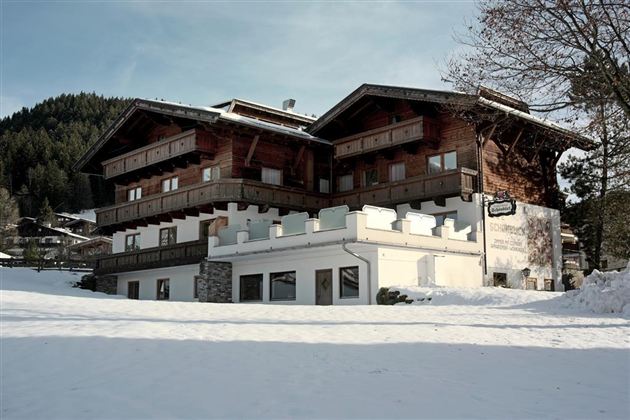 An Alpine chalet in the snow, surrounded by mountains. The wooden architecture and winter magic give the scene a cozy atmosphere.