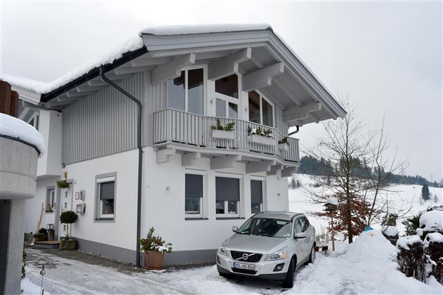 Ein schönes Haus im Winter mit Schnee bedeckt. Ein Pkw steht auf der Einfahrt vor dem Gebäude.