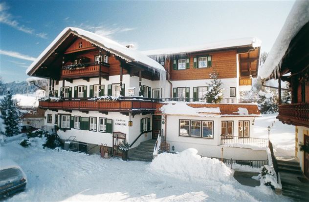 Ein charmantes Haus im klassischen Alpenstil, umgeben von Schnee. Die Atmosphäre ist gemütlich und einladend.