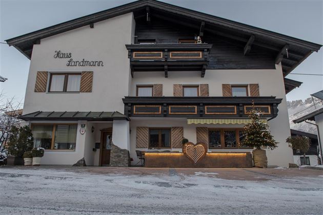 Ein charmantes Gebäude mit dem Namen "Haus Landmann". Es zeigt eine alpine Architektur und ist von Schnee umgeben.